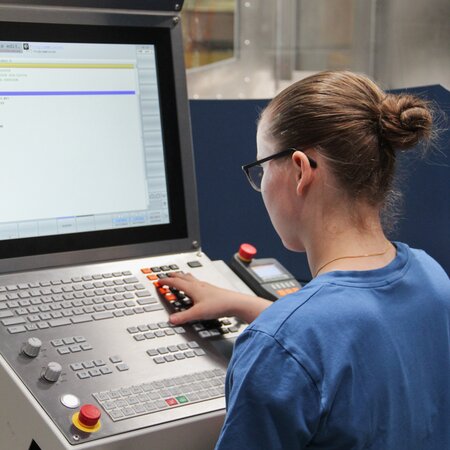 Polymechanikerin programmiert den Ablauf der Produktion an der computergesteuerte CNC-Maschine | © 2023 Lehrberufe | Woche-Pass AG